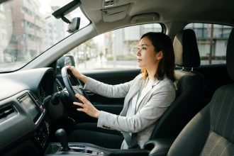 Femme au volant d'une voiture à boîte automatique, vue depuis le siège passager, avec le sélecteur de vitesses automatique visible sur le tableau de bord
